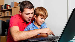 Vater mit Kind vor einem Laptop